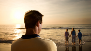 man watching family from distance at sunset